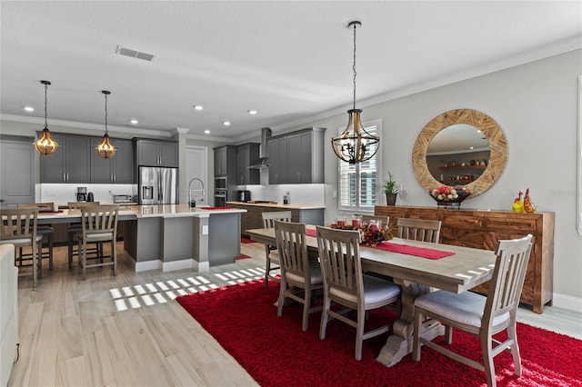 dining room with light hardwood / wood-style flooring, an inviting chandelier, and ornamental molding