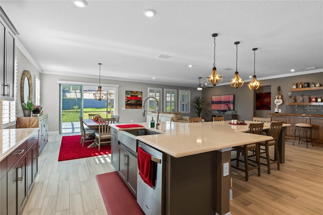 kitchen featuring dishwasher, a large island with sink, pendant lighting, and sink