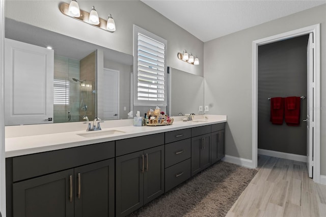 bathroom with a textured ceiling, vanity, wood-type flooring, and walk in shower