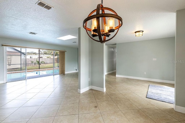 spare room with light tile patterned flooring and a notable chandelier