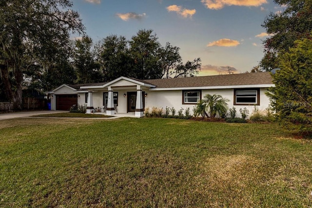 ranch-style home with covered porch, a garage, and a lawn