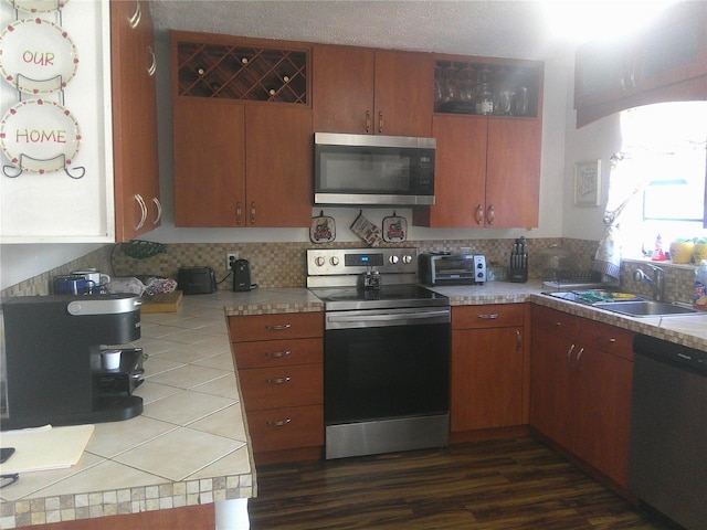 kitchen with dark hardwood / wood-style flooring, tasteful backsplash, a textured ceiling, stainless steel appliances, and sink