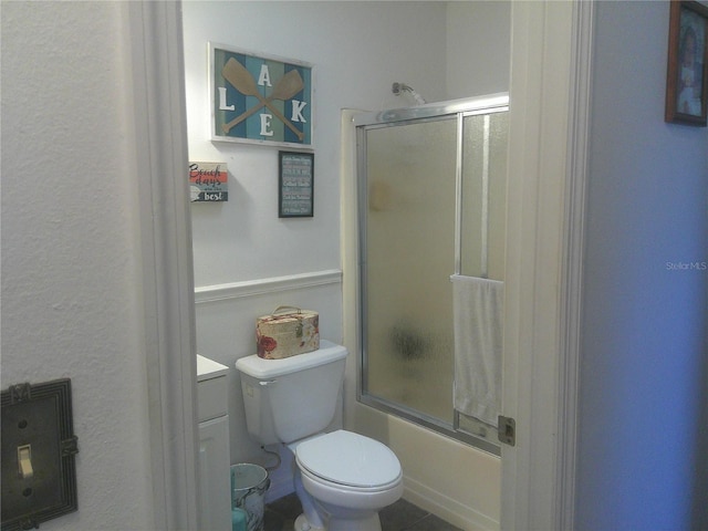 full bathroom featuring tile patterned floors, vanity, bath / shower combo with glass door, and toilet