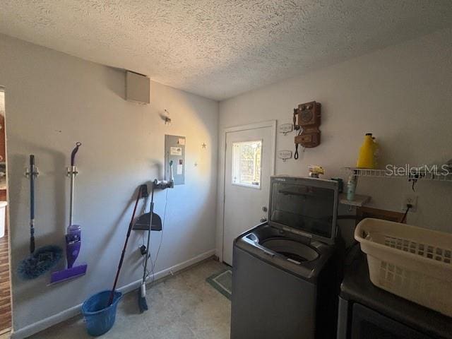 washroom with washer / clothes dryer, electric panel, and a textured ceiling