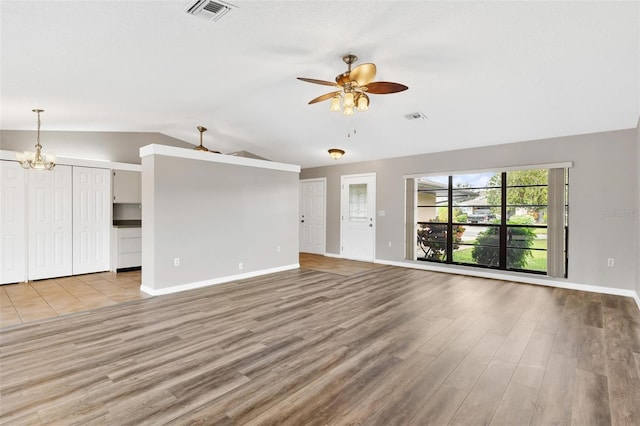 unfurnished living room featuring light hardwood / wood-style flooring, ceiling fan with notable chandelier, and lofted ceiling