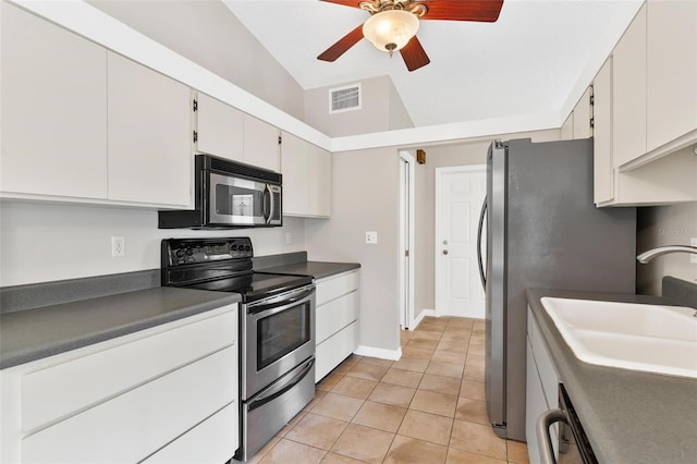 kitchen featuring appliances with stainless steel finishes, sink, light tile patterned floors, white cabinetry, and lofted ceiling