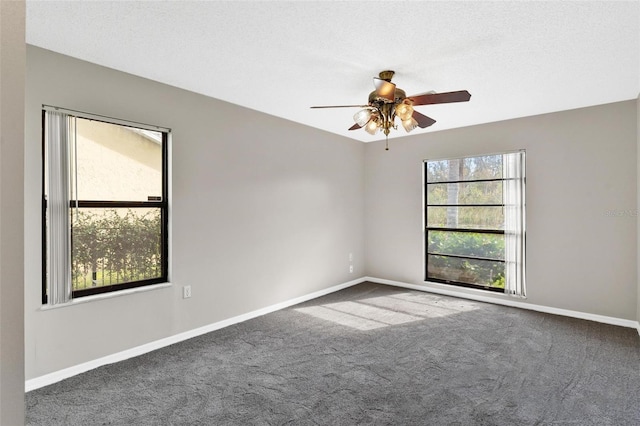 unfurnished room with dark carpet, plenty of natural light, and ceiling fan