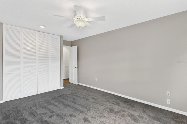 unfurnished bedroom with dark colored carpet, ceiling fan, and a closet