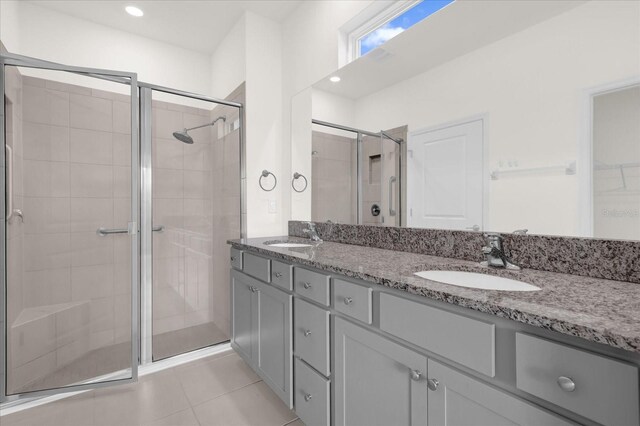 bathroom with a shower with door, vanity, and tile patterned flooring