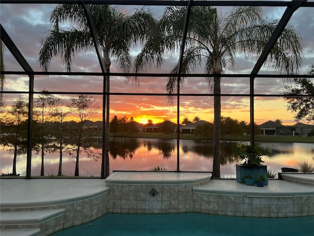 pool at dusk with a lanai and a water view