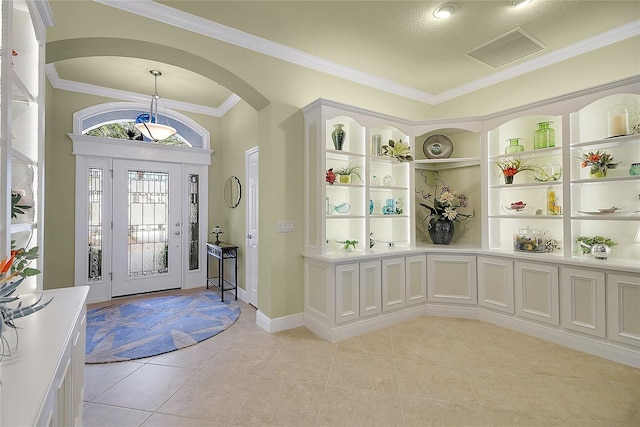 entryway with light tile patterned floors and crown molding