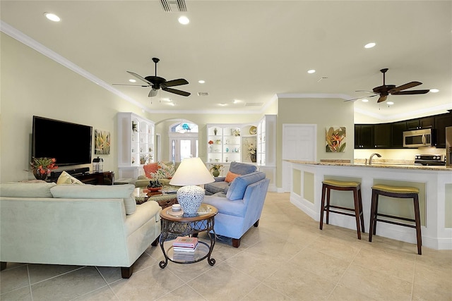 tiled living room featuring ceiling fan, sink, and ornamental molding