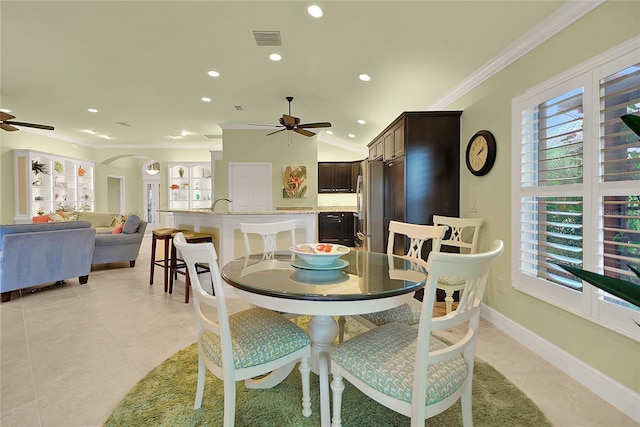 dining room with ceiling fan, built in features, crown molding, lofted ceiling, and light tile patterned flooring