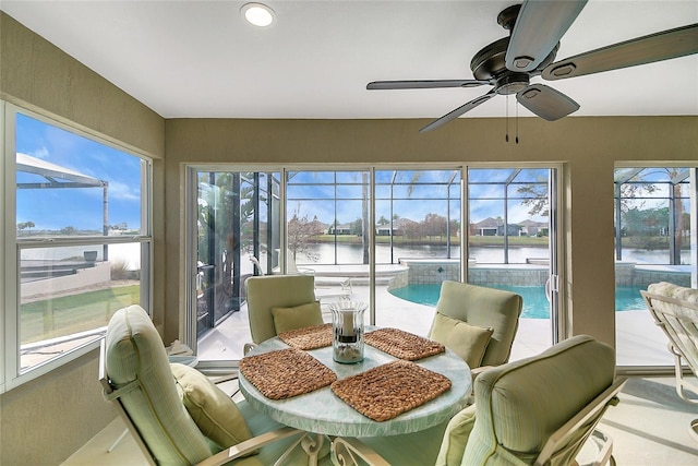 sunroom / solarium with ceiling fan and a water view