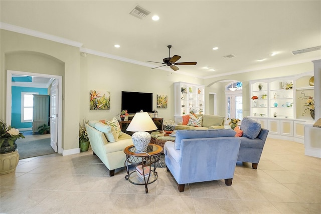 tiled living room featuring french doors, built in features, ceiling fan, and crown molding