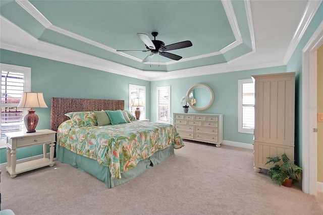 carpeted bedroom with ceiling fan, a tray ceiling, and multiple windows