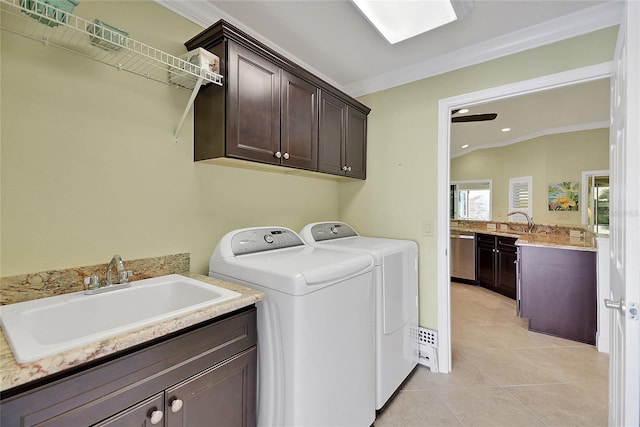 clothes washing area featuring cabinets, ornamental molding, sink, light tile patterned floors, and washing machine and clothes dryer