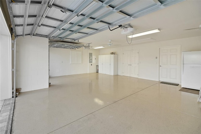 garage featuring electric panel, white fridge, a garage door opener, and ceiling fan