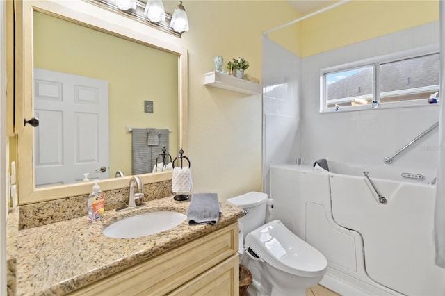 bathroom with a washtub, vanity, and toilet