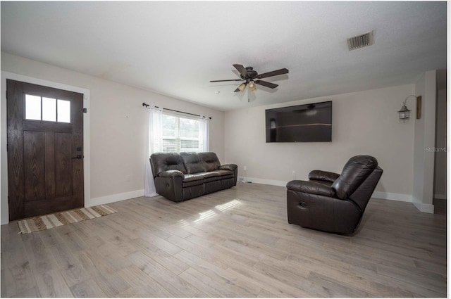 living room with a ceiling fan, light wood-style flooring, baseboards, and visible vents