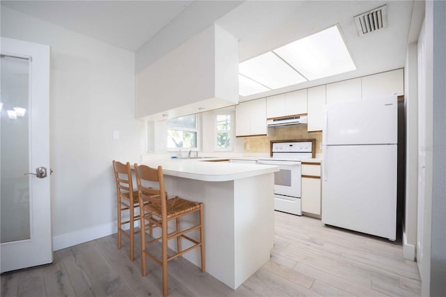 kitchen featuring white appliances, visible vents, range hood, and white cabinetry