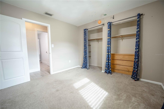 unfurnished bedroom with baseboards, visible vents, multiple closets, and carpet flooring