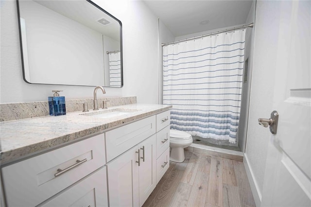 full bathroom with toilet, vanity, a shower with curtain, wood finished floors, and visible vents