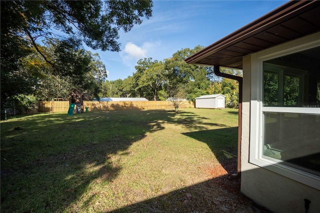 view of yard with a fenced backyard, a shed, an outbuilding, and a playground