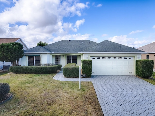 single story home featuring cooling unit, a garage, and a front yard