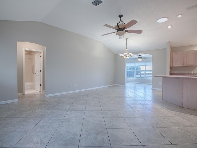 unfurnished living room featuring ceiling fan with notable chandelier, light tile patterned floors, and vaulted ceiling