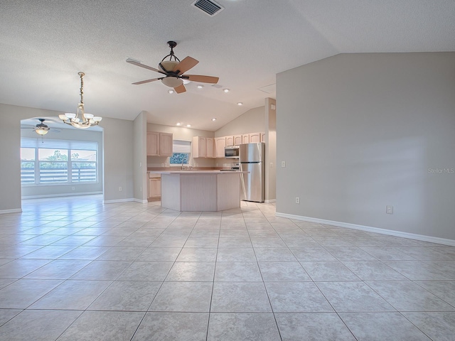 kitchen with appliances with stainless steel finishes, light tile patterned floors, vaulted ceiling, and hanging light fixtures