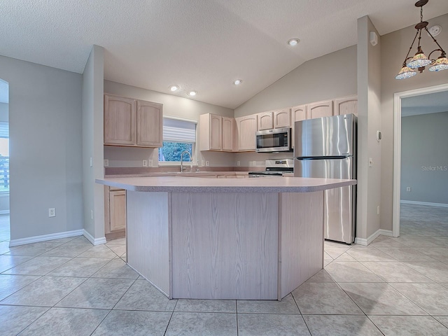 kitchen featuring appliances with stainless steel finishes, light brown cabinetry, vaulted ceiling, an inviting chandelier, and a kitchen island