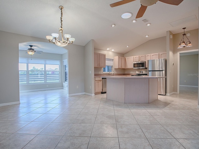 kitchen featuring appliances with stainless steel finishes, vaulted ceiling, light brown cabinets, a center island, and light tile patterned flooring