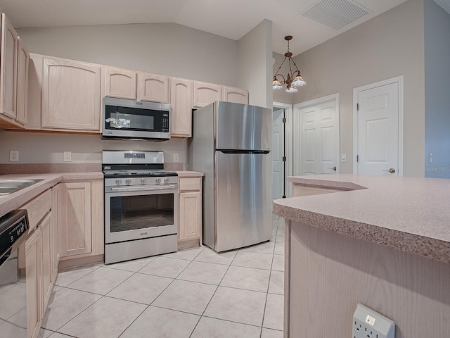 kitchen with stainless steel appliances, an inviting chandelier, hanging light fixtures, lofted ceiling, and light tile patterned flooring