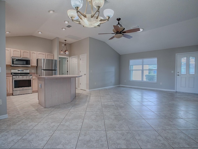 kitchen featuring lofted ceiling, ceiling fan with notable chandelier, hanging light fixtures, appliances with stainless steel finishes, and a kitchen island