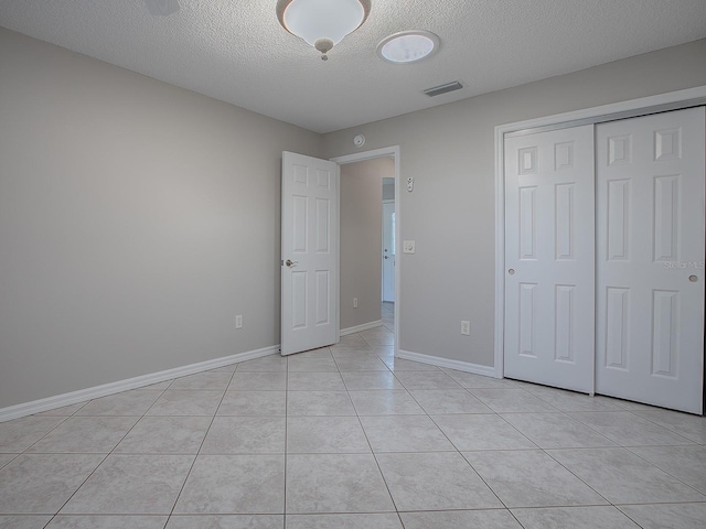 unfurnished bedroom featuring light tile patterned floors, a textured ceiling, and a closet