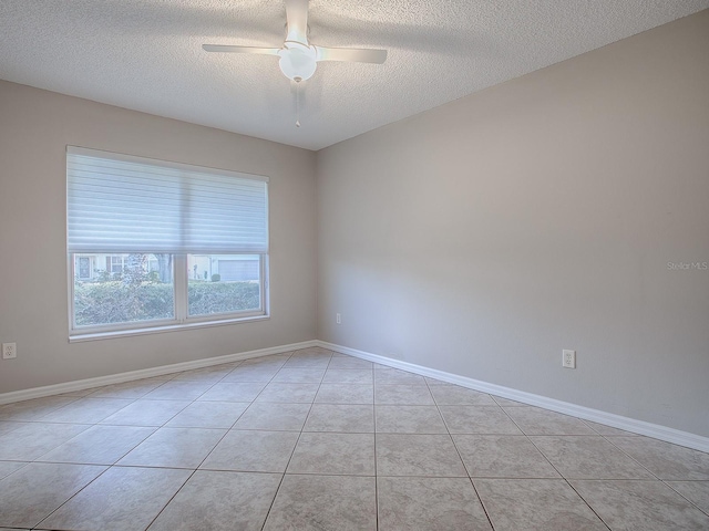 empty room featuring ceiling fan, light tile patterned flooring, and a textured ceiling