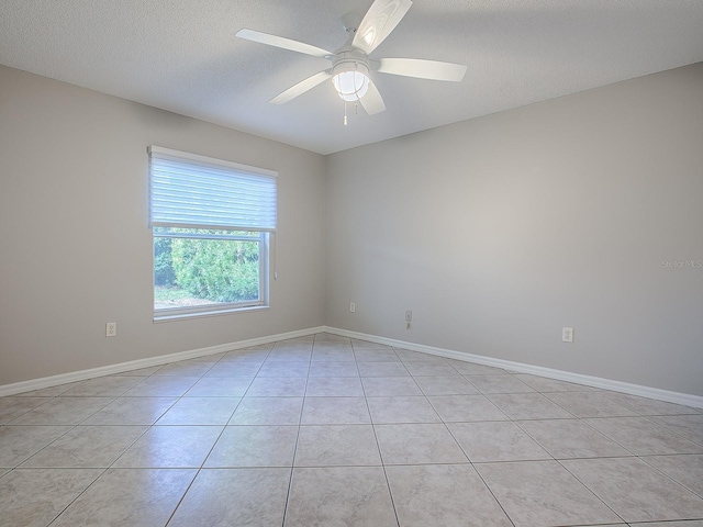 empty room with ceiling fan, light tile patterned floors, and a textured ceiling