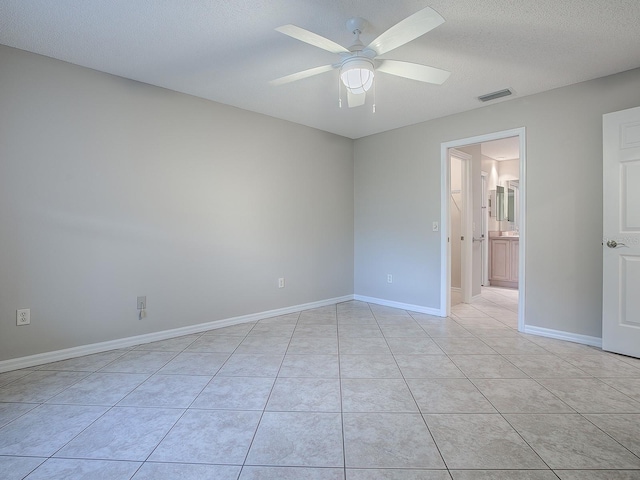 unfurnished room featuring ceiling fan, light tile patterned floors, and a textured ceiling