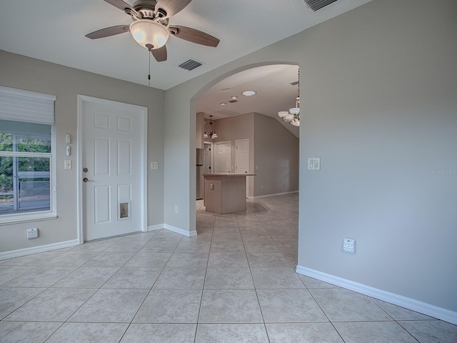 tiled spare room featuring ceiling fan with notable chandelier and a textured ceiling