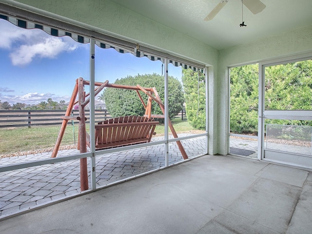 unfurnished sunroom featuring ceiling fan and a wealth of natural light