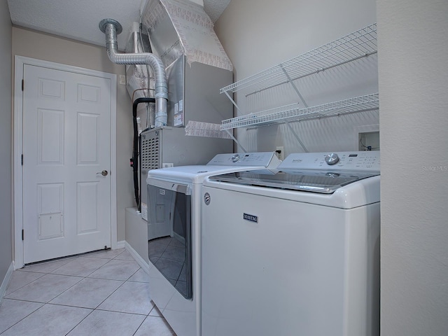 laundry area with washer and clothes dryer and light tile patterned flooring