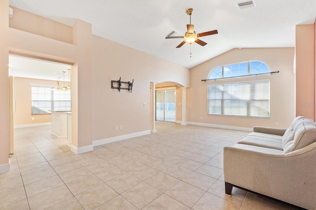 unfurnished room with lofted ceiling, light tile patterned flooring, a healthy amount of sunlight, and ceiling fan with notable chandelier