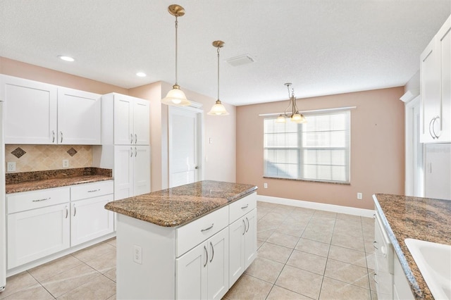 kitchen with decorative light fixtures, white cabinetry, backsplash, and light tile patterned floors