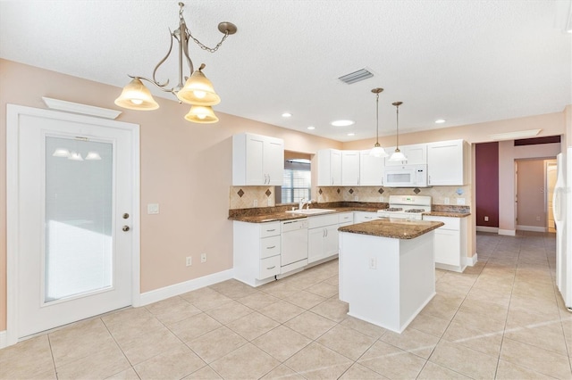 kitchen featuring pendant lighting, a center island, white appliances, and white cabinetry