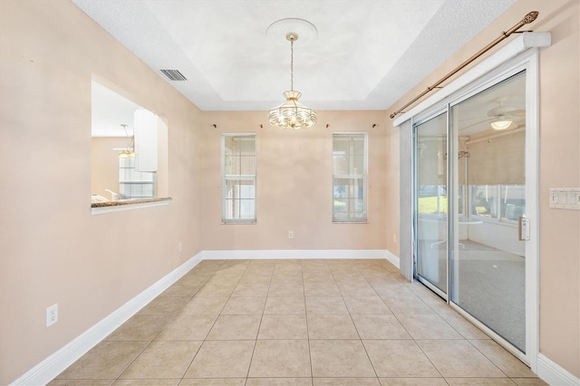 unfurnished room featuring a chandelier, a textured ceiling, and light tile patterned flooring