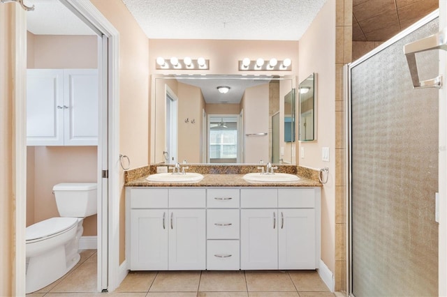 bathroom with tile patterned floors, vanity, a textured ceiling, toilet, and a shower with shower door