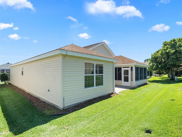 view of side of property with a sunroom and a lawn