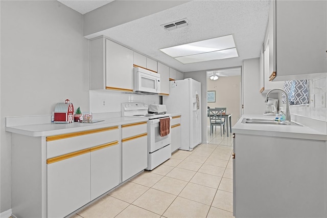 kitchen with white appliances, white cabinets, sink, ceiling fan, and light tile patterned floors