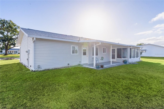 rear view of property featuring a yard, a patio, and a sunroom